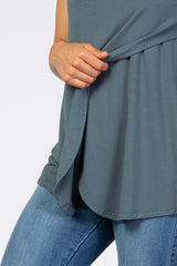 woman wearing a dark teal sleeveless top with a relaxed fit, paired with blue jeans