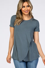 woman wearing a teal short sleeve top with an asymmetrical hem and a relaxed fit, paired with jeans