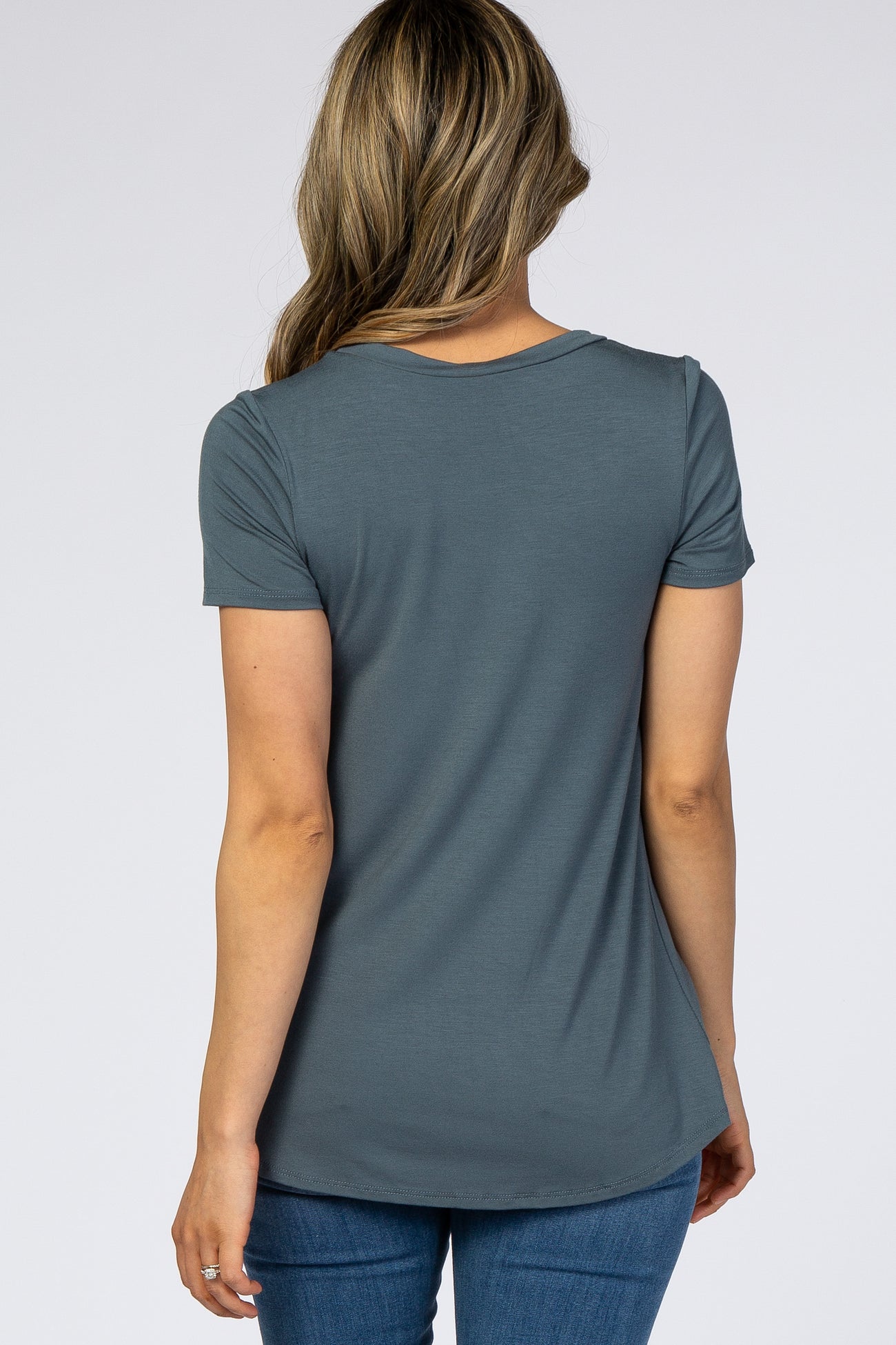 woman wearing a dark teal short sleeve top, shown from the back, with a relaxed fit and rounded hem