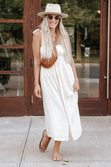 woman wearing a cream sleeveless maxi dress with a front pocket and a brown crossbody bag, smiling outdoors
