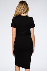 woman wearing a black short sleeve maternity dress with side ruching, showing a fitted silhouette from the back