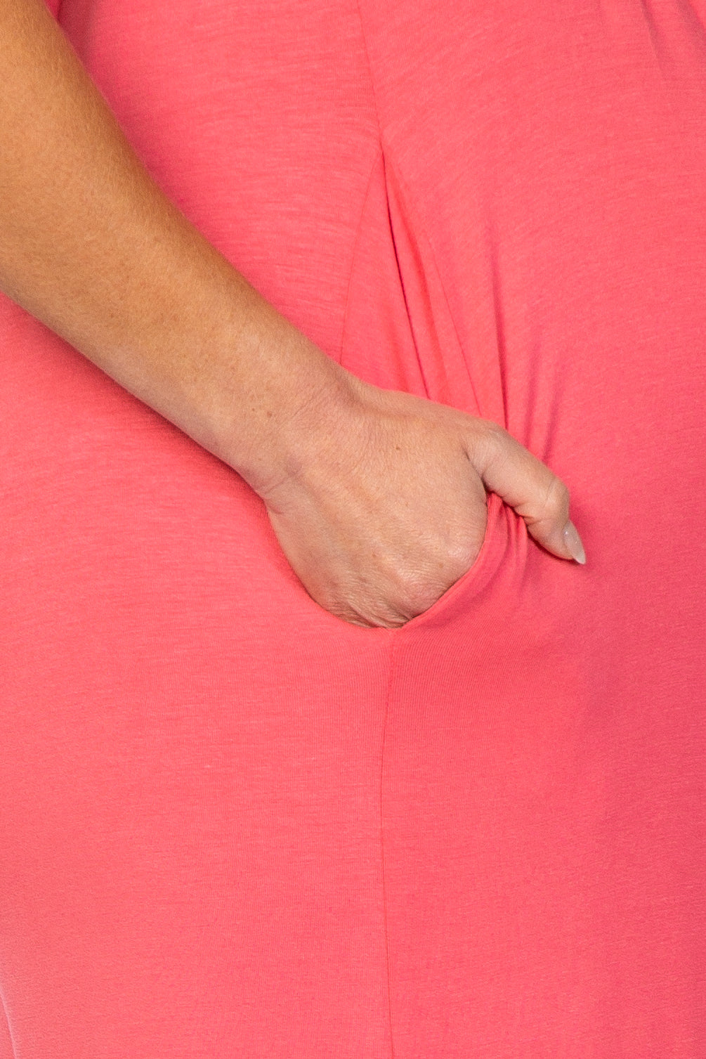 close-up of a pregnant belly in a coral maternity dress with a side pocket