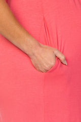 close-up of a pregnant belly in a coral maternity dress with a side pocket