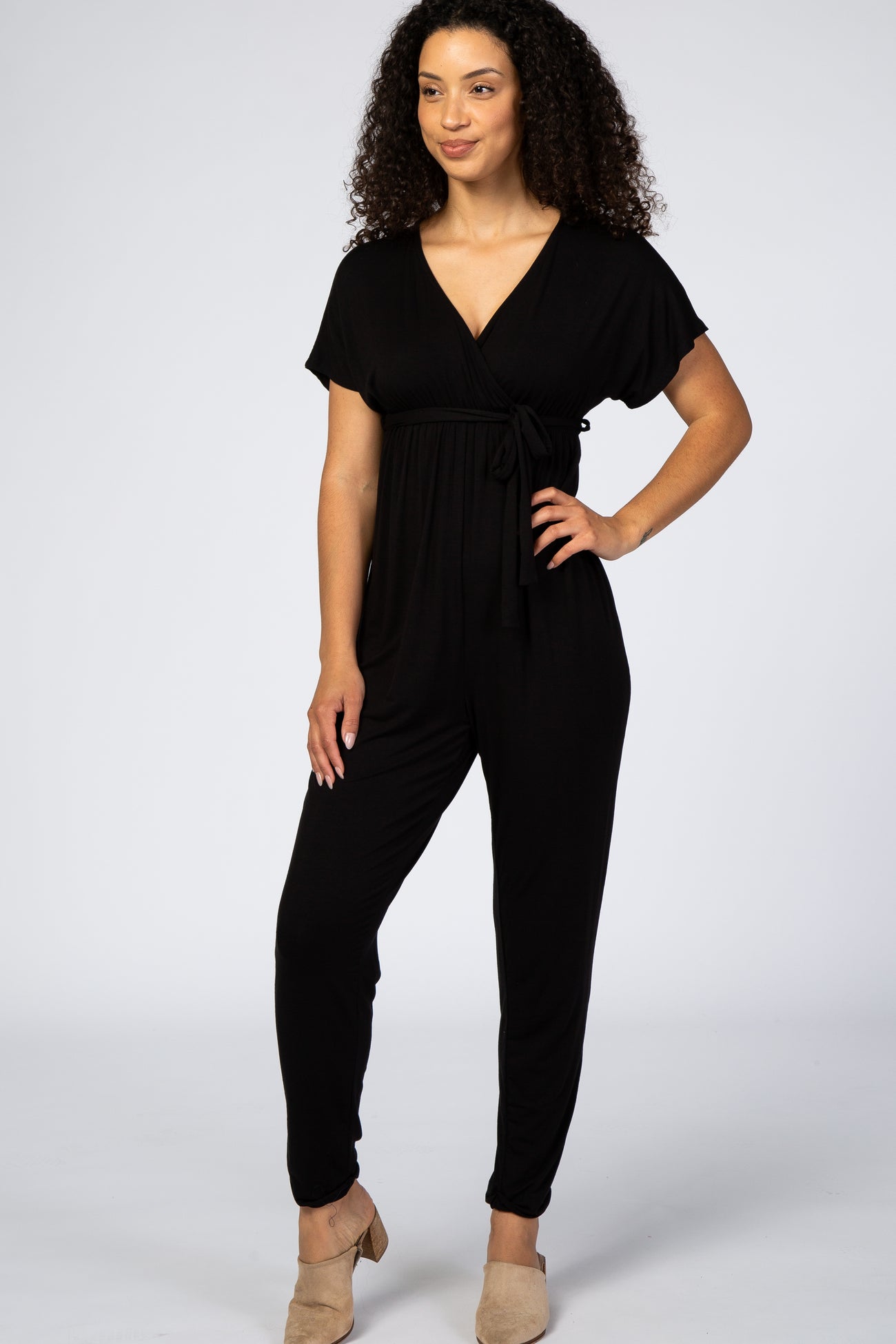 woman wearing a black short sleeve wrap jumpsuit with a tie waist and relaxed fit