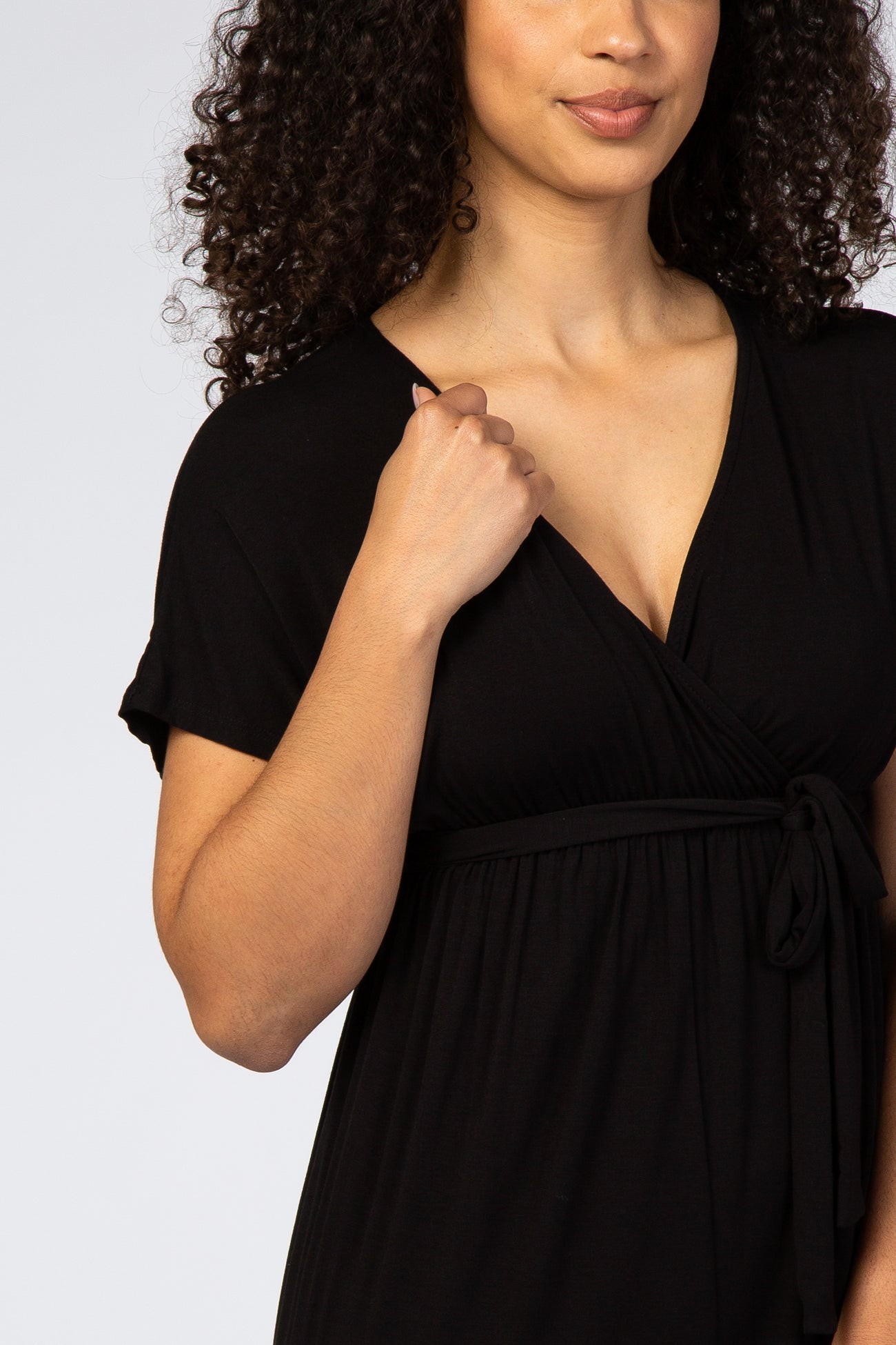 woman wearing a black wrap dress with short sleeves and a tie detail at the waist