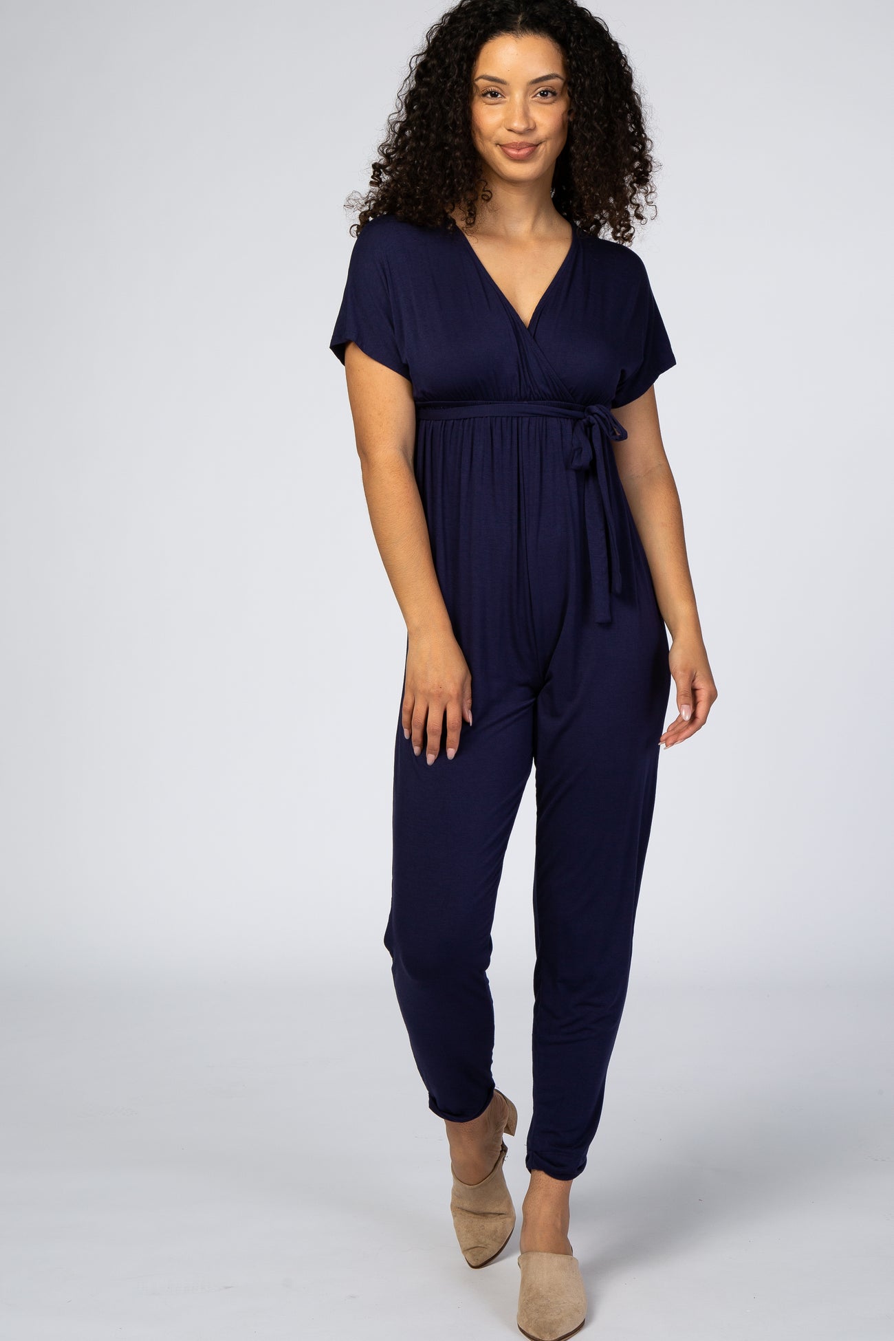 woman wearing a navy blue short sleeve jumpsuit with a wrap front and tie waist detail