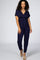woman wearing a navy blue short sleeve jumpsuit with a wrap front and tie waist detail