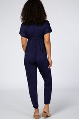 woman wearing a navy blue short sleeve jumpsuit with a cinched waist, shown from the back