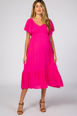 woman wearing a bright pink short sleeve maternity dress with a tiered skirt and a v-neckline, showing her baby bump