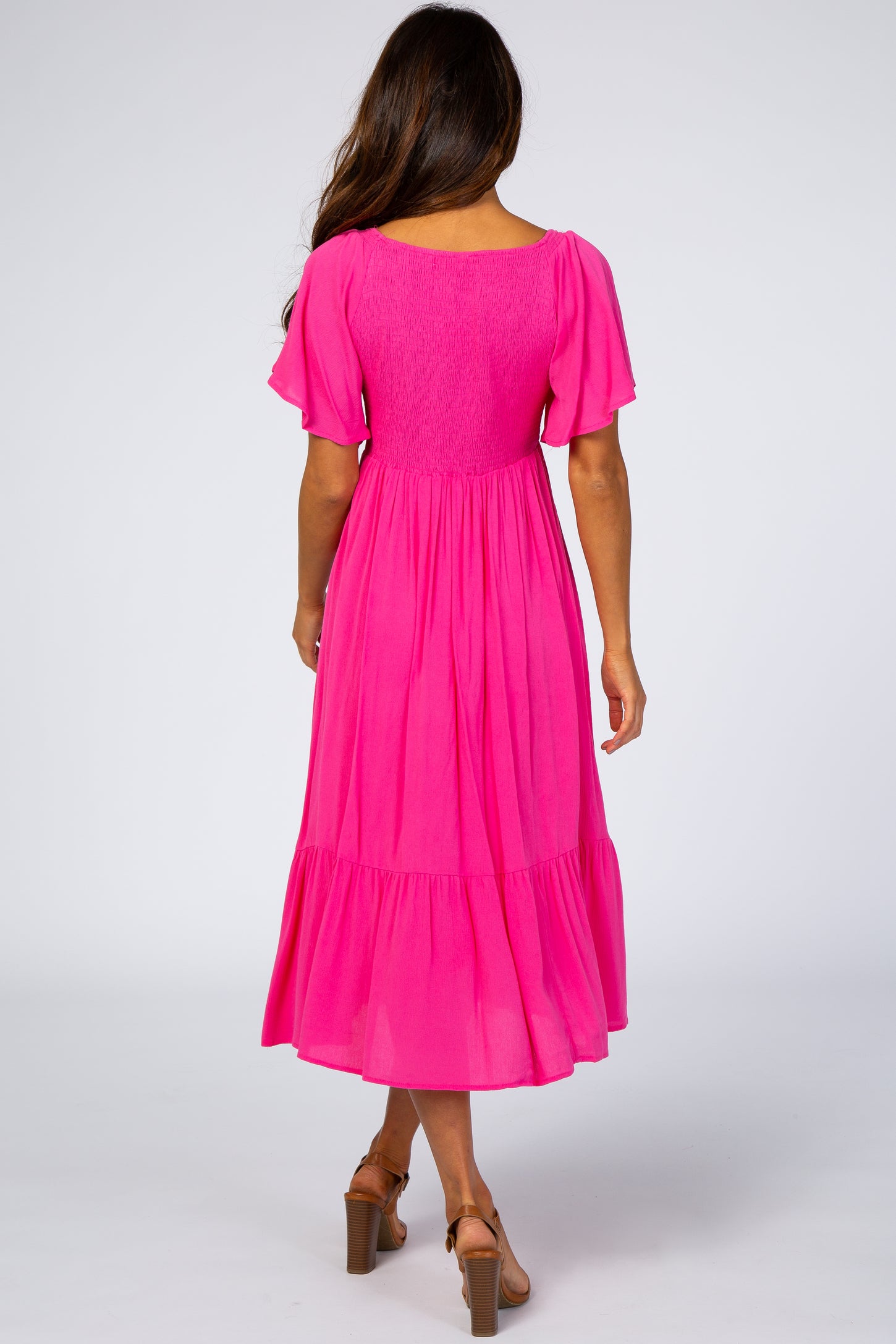 woman wearing a bright pink short sleeve maxi dress with a smocked back and tiered skirt