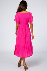 woman wearing a bright pink short sleeve maxi dress with a smocked back and tiered skirt