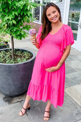 woman wearing a bright pink maternity dress with flutter sleeves and a tiered skirt, holding a cone of ice cream and cradling her baby bump
