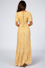 woman wearing a yellow floral maxi dress with short sleeves and a smocked back detail, shown from the back