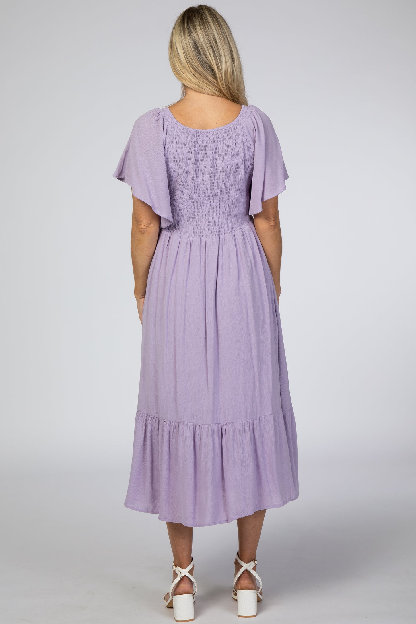 woman wearing a lavender maternity dress with flutter sleeves and a tiered skirt, showing her back