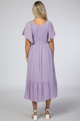 woman wearing a lavender maternity dress with flutter sleeves and a tiered skirt, showing her back