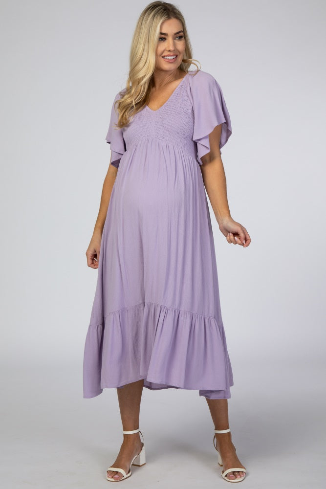 woman wearing a lavender maternity dress with flutter sleeves and a tiered skirt, showcasing a baby bump