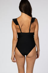 woman wearing a black ruffled one-piece swimsuit, showing the back view and adjustable straps