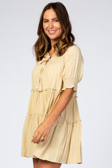 woman wearing a light yellow tiered maternity dress with short puff sleeves and tassel neck tie
