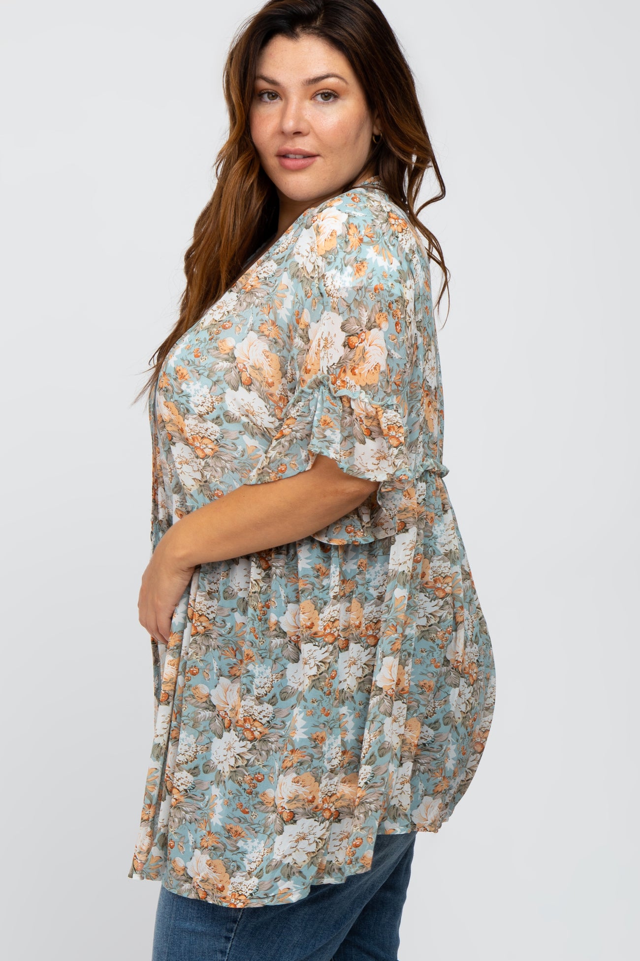 woman wearing a light blue floral print kimono with ruffled sleeves and blue jeans