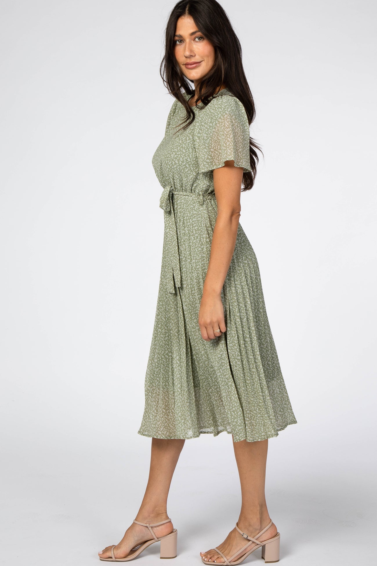 woman wearing a green floral midi dress with short sleeves and a tied waist detail