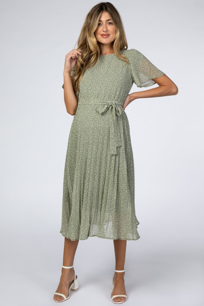 woman wearing a green floral print maternity dress with short sleeves and a tie waist, showcasing her baby bump