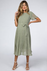 woman wearing a green floral print maternity dress with short sleeves and a tie waist, showcasing her baby bump