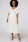 woman wearing a white midi dress with a smocked bodice and flutter sleeves, standing on a plain background