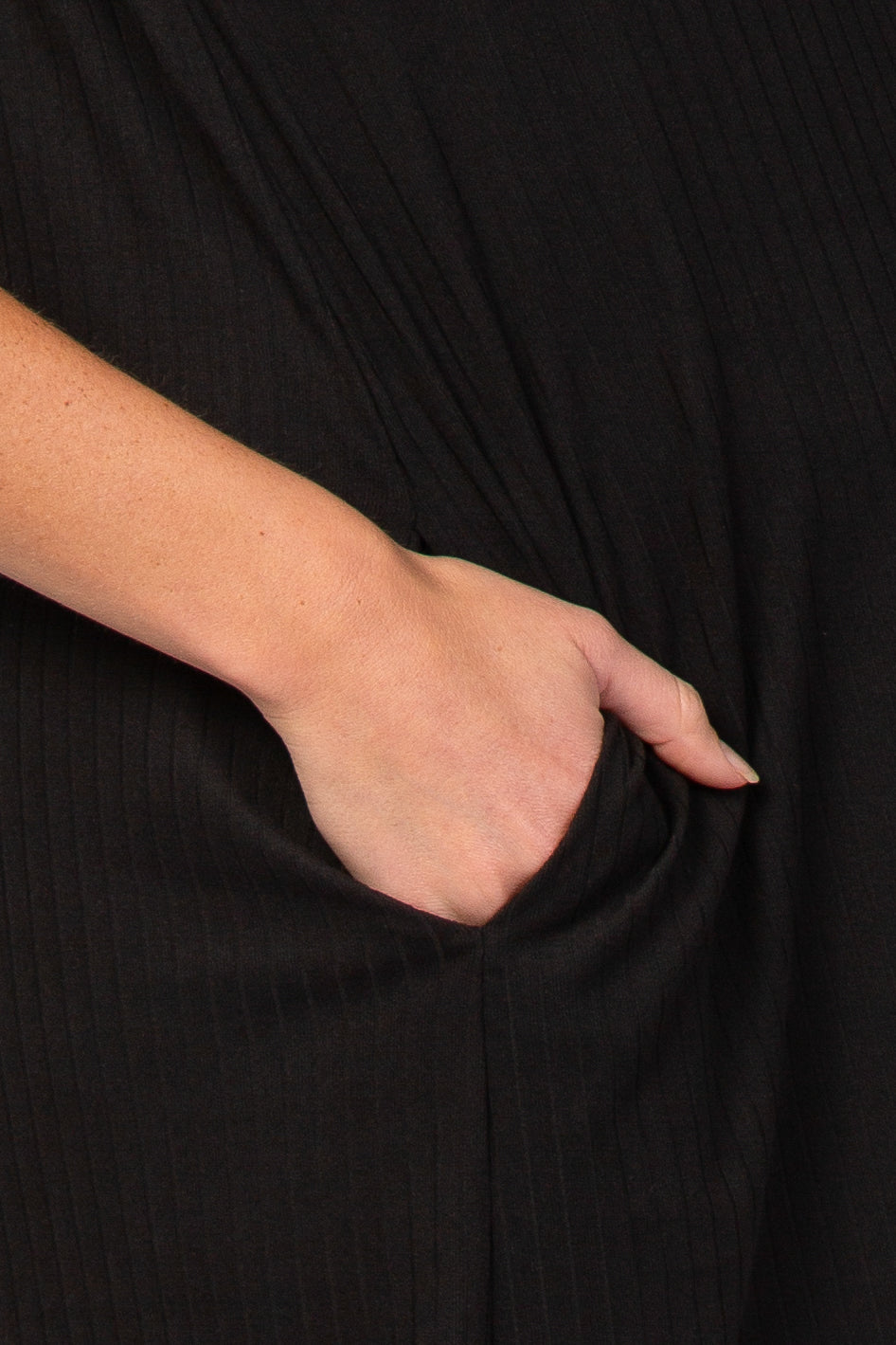 close-up of a hand in the pocket of a black maternity dress with vertical ribbed texture