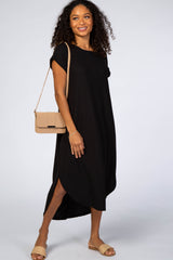 woman wearing a black short sleeve midi dress with a tan crossbody bag and matching sandals