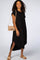 woman wearing a black short sleeve midi dress with a tan crossbody bag and matching sandals