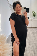woman wearing a black short sleeve maternity dress with a side slit and holding her baby bump