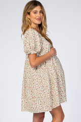 Pregnant woman in a floral puff sleeve maternity dress holding her baby bump against a white background
