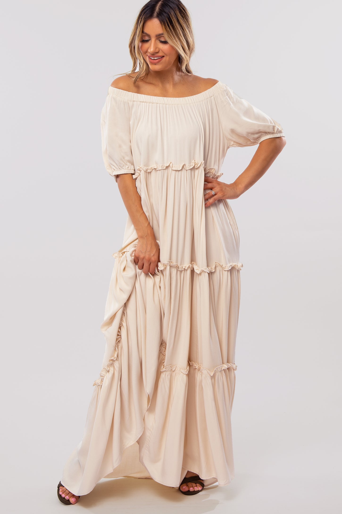 woman wearing a beige off-the-shoulder maxi dress with ruffles and short sleeves