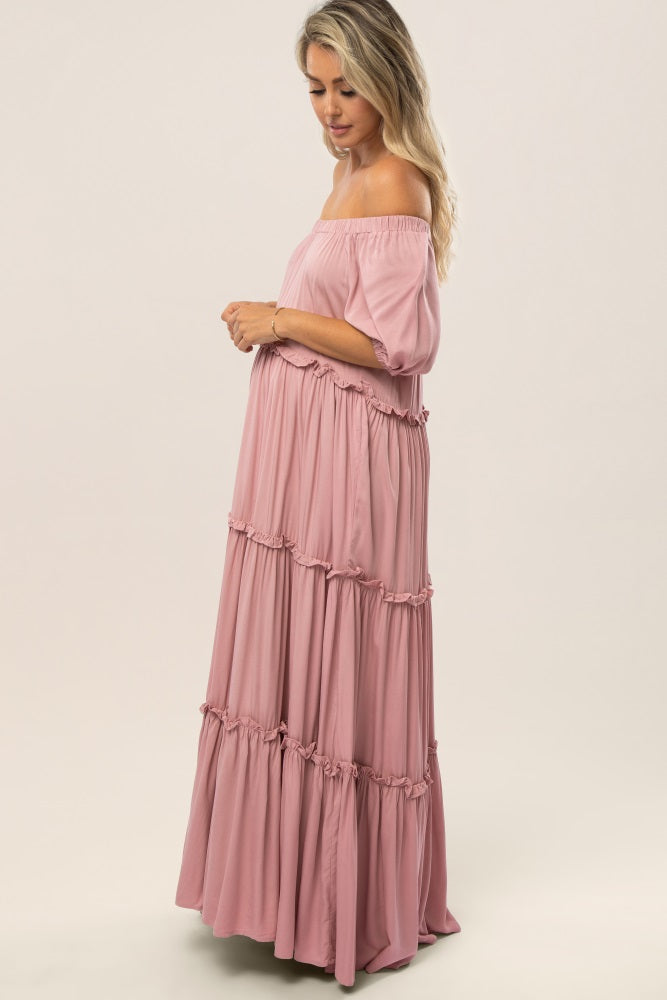 woman wearing a pink off-the-shoulder maternity maxi dress with tiered ruffles and a visible baby bump