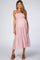 woman wearing a pink and white gingham maternity dress with smocked bodice and tiered skirt, showing her baby bump