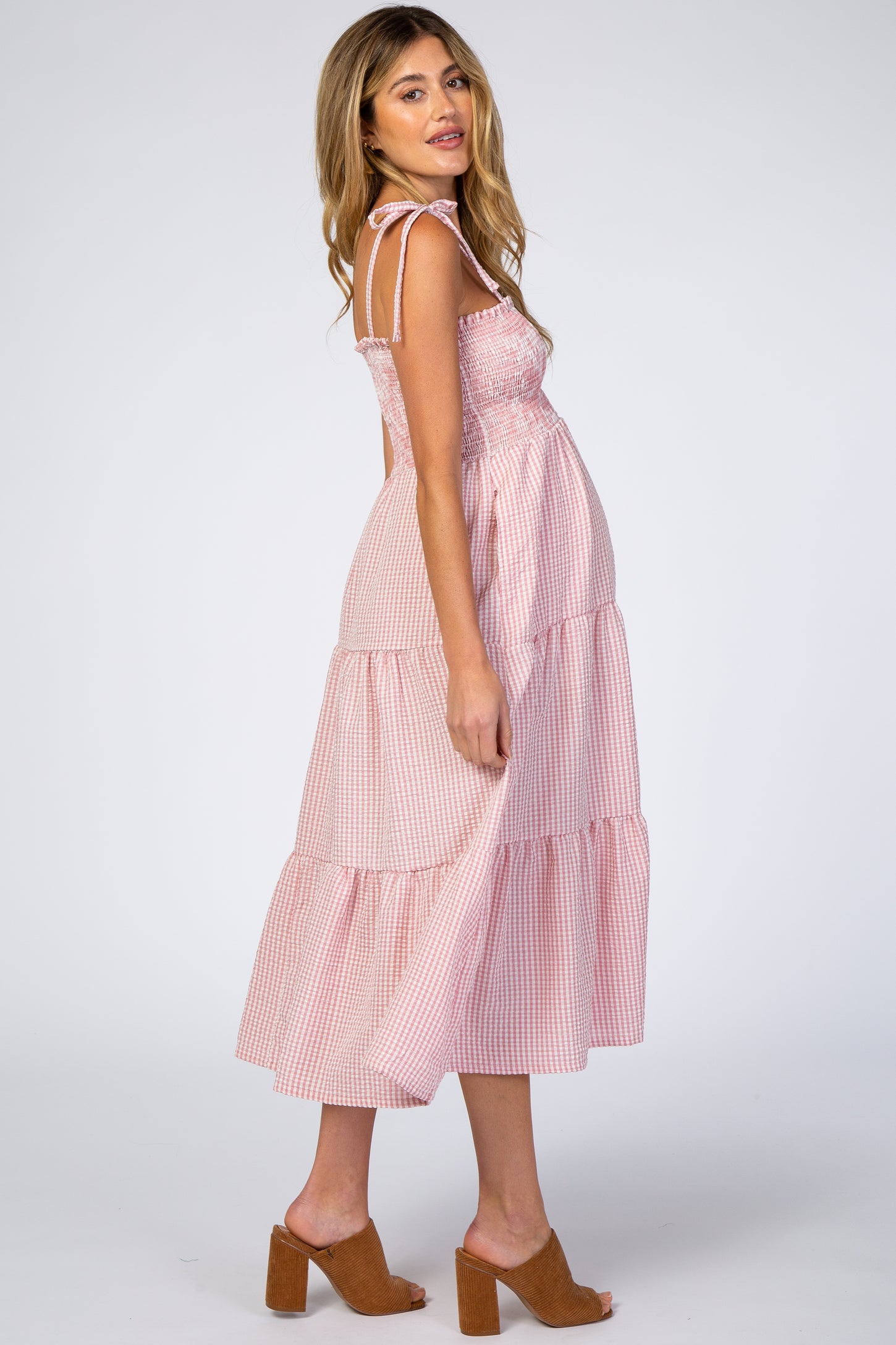 woman wearing a red and white gingham maternity maxi dress with tied straps and a visible baby bump