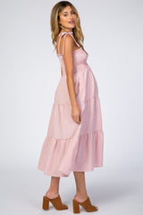 woman wearing a red and white gingham maternity maxi dress with tied straps and a visible baby bump