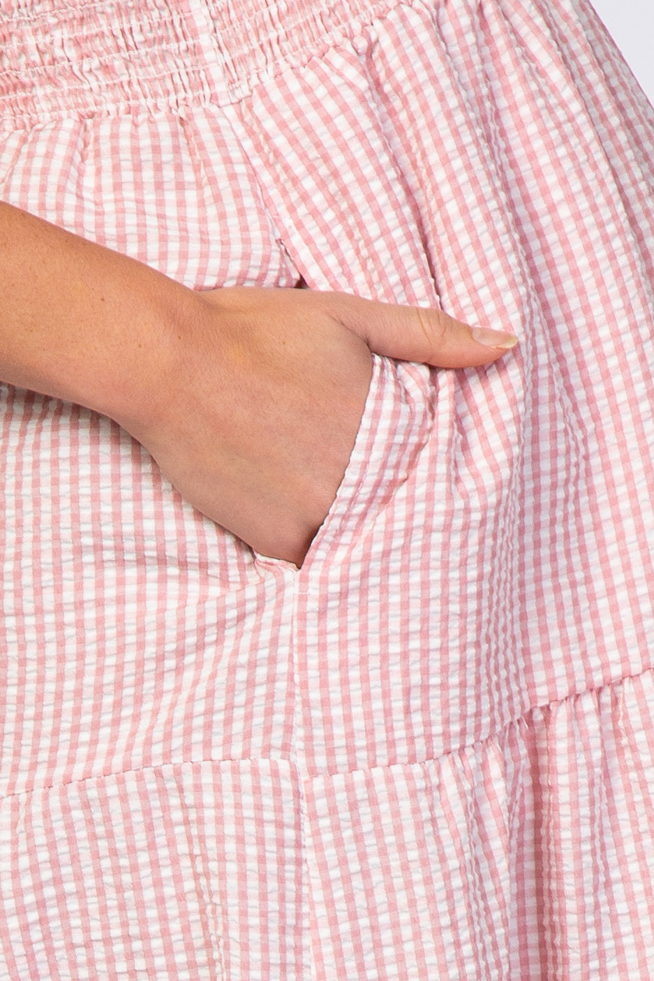 maternity wear pink and white gingham dress with elastic waistband and side pockets, model showing hand in pocket