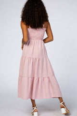 woman wearing a pink and white checked maxi dress with a smocked bodice and tiered skirt standing from the back