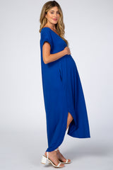 woman wearing a blue maternity maxi dress with short sleeves and side pockets, showcasing her baby bump
