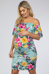 woman wearing a floral off-shoulder maternity dress and holding her baby bump