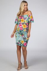woman wearing a light blue off-the-shoulder floral maternity dress with a fitted silhouette and a visible baby bump
