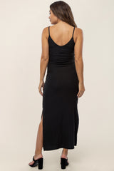 woman wearing a black ribbed maternity dress with a v-back and side slit, showing a baby bump