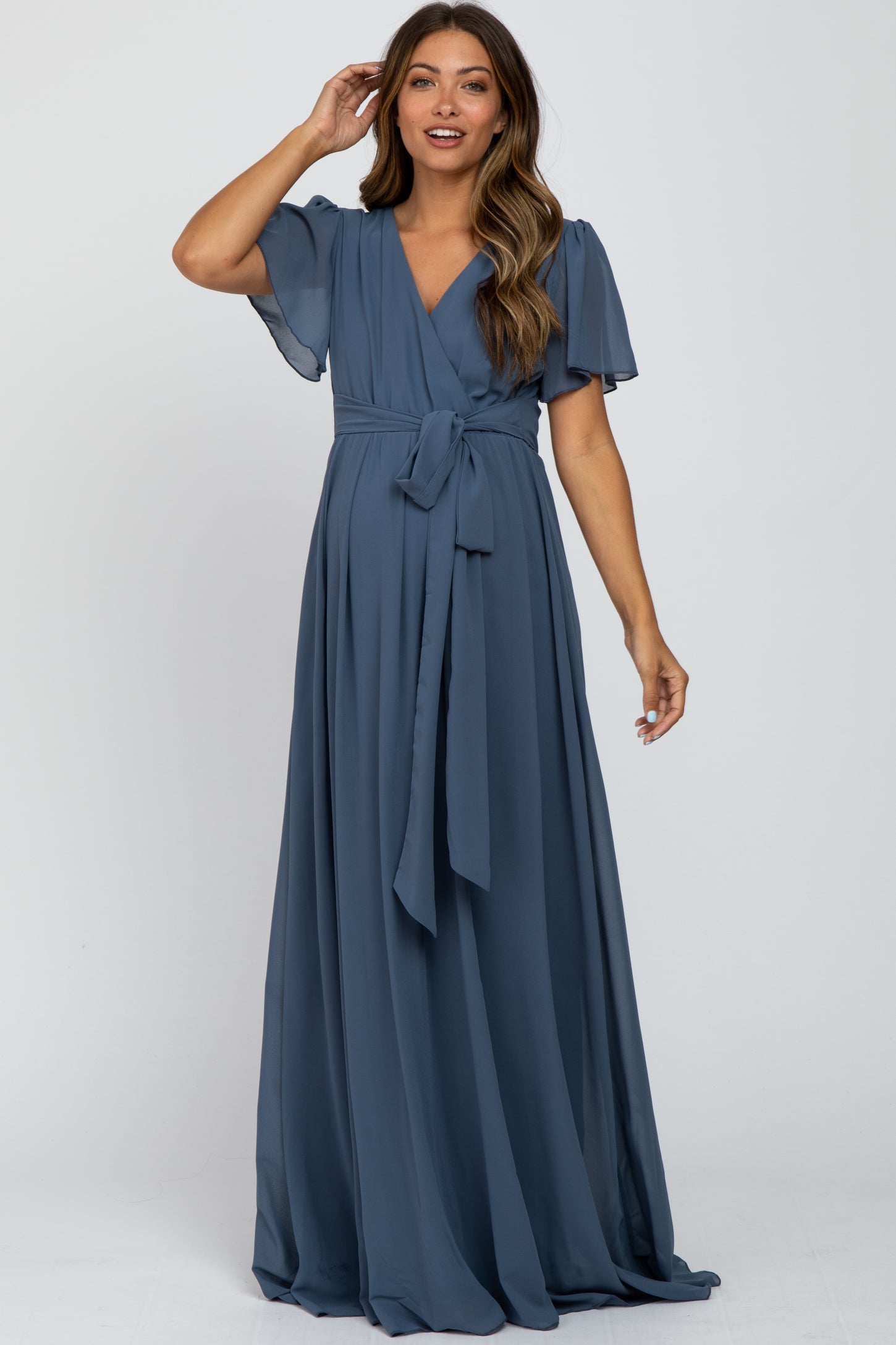 woman wearing a blue maternity wrap dress with flutter sleeves and a tie waist