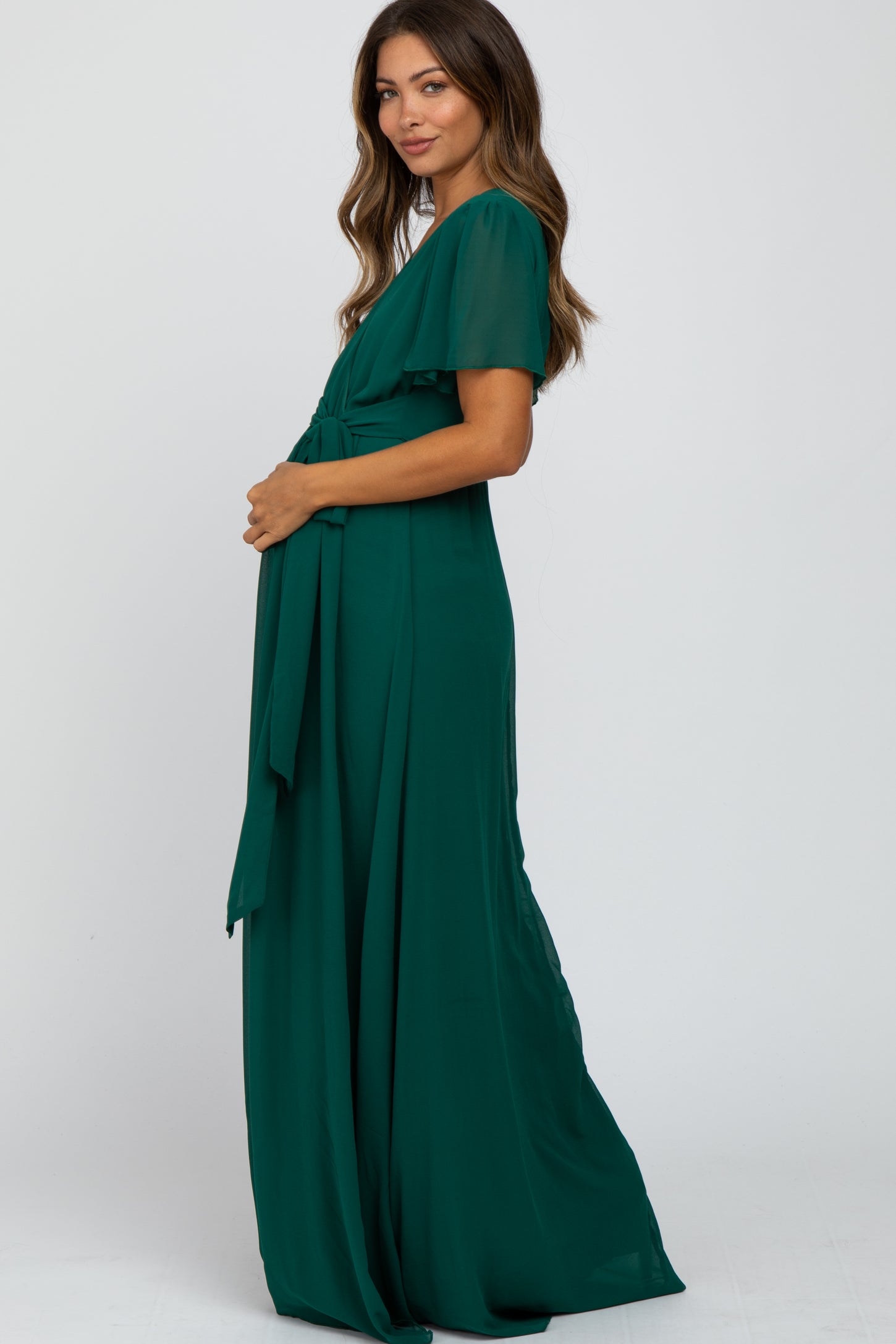 woman in a forest green short sleeve maternity maxi dress with a waist tie against a white background