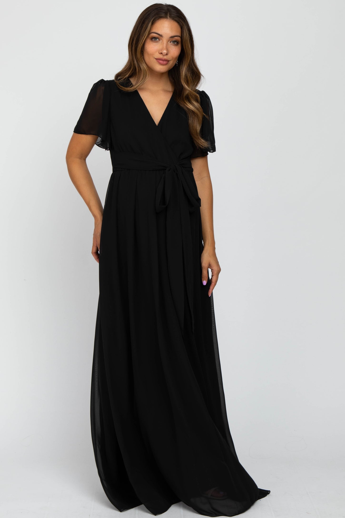 woman wearing a black maxi maternity dress with short sheer sleeves and a tied waist detail