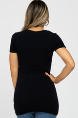 Back view of a woman wearing a fitted black short-sleeve t-shirt and blue jeans against a white background