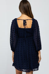 woman wearing a navy blue maternity dress with puff sleeves and a smocked back design