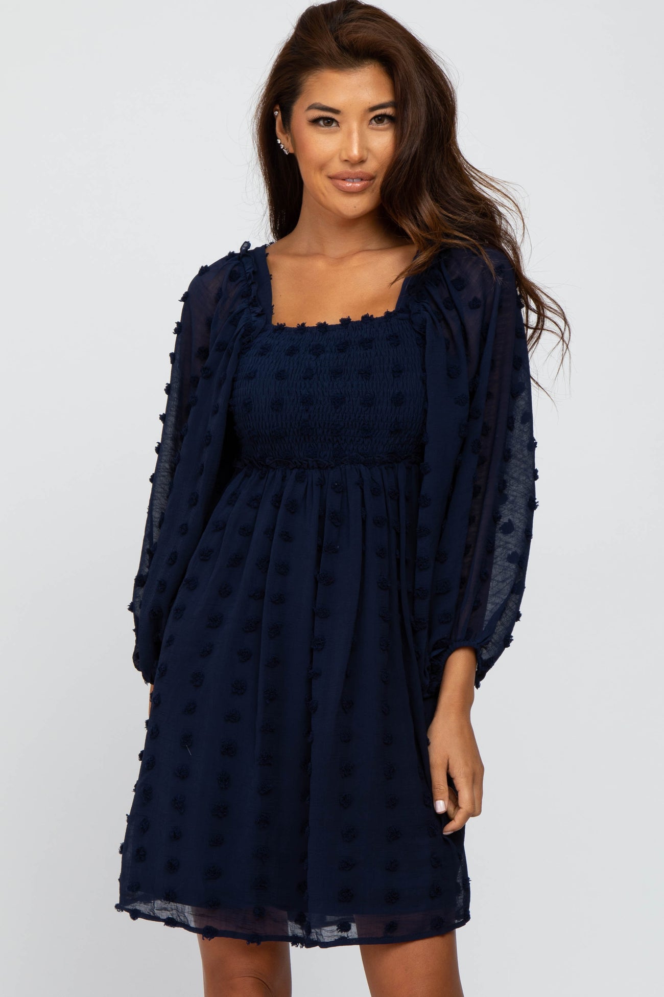 woman wearing a navy blue dress with puff sleeves and textured dot detailing on the fabric