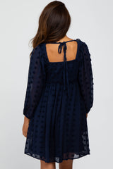 women wearing a navy blue short dress with puff sleeves and a back tie detail, featuring textured dots throughout